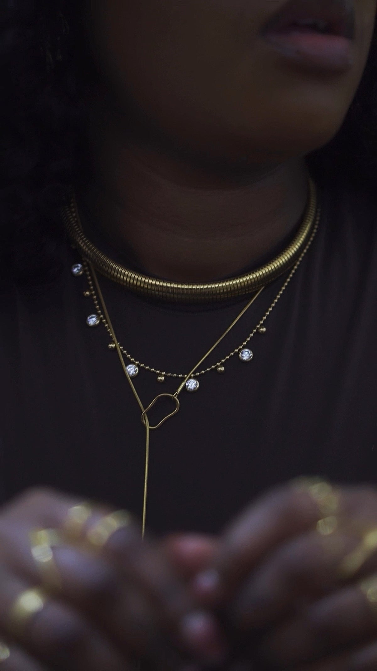 Layered gold necklaces: a snake chain choker, a crystal drop chain and a lariat